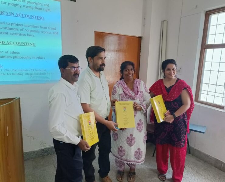 Group of four people holding yellow bound theses at a presentation ceremony in a classroom