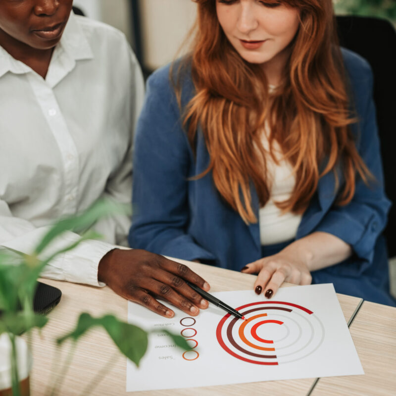 Focus on a diverse woman hands pointing on charts on a desk Business colleagues analyzing data chart