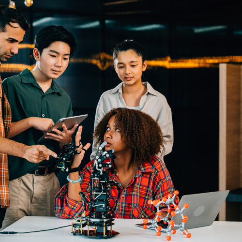 In a classroom at school students and teacher study and experiment on a robotic arm. Encouraging innovation teamwork and practical learning in education. Robot hand. Innovation and technology concept Students collaborating on robotics project